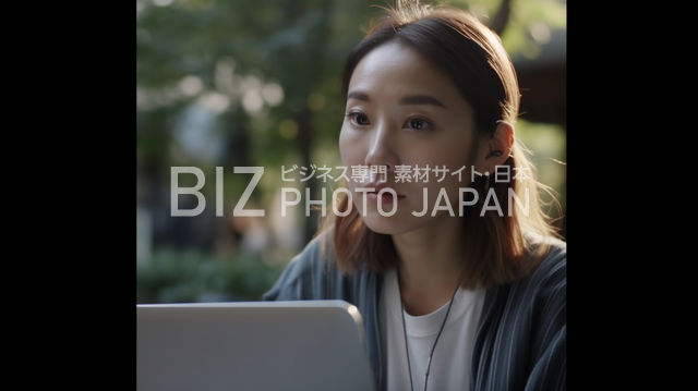 外でカメラを見ながらパソコン操作する日本人女性の写真素材