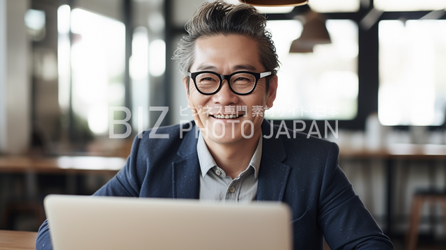 笑顔の日本人男性がラップトップを使っている