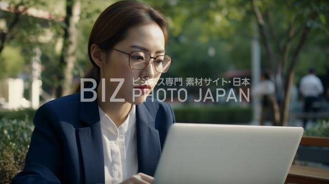 屋外でノートパソコンを操作する日本人ビジネスウーマン