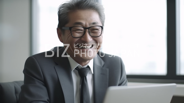 ノートパソコンを操作する日本人男性の笑顔