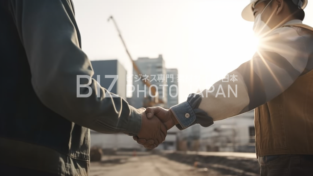 都市のバックグラウンドと握手する建設作業員たち