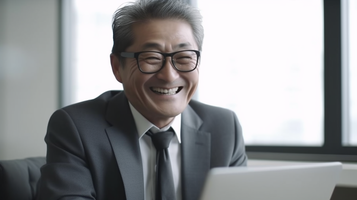 ノートパソコンを操作する日本人男性の笑顔