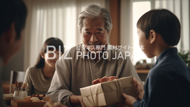 家族の笑顔が溢れる瞬間！白髪の男性が中年男性からプレゼントを受け取った感動の瞬間を、他の家族が見つめる材