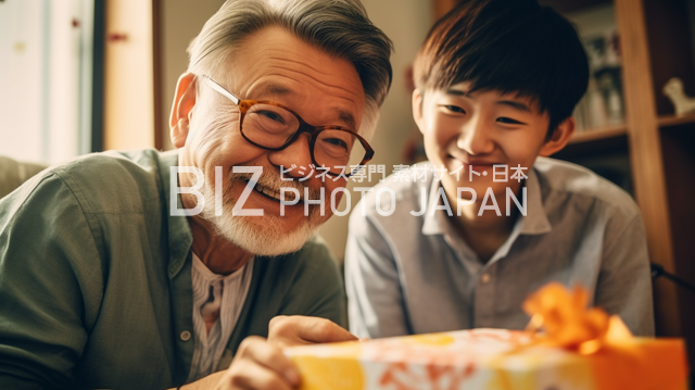 白髪の男性と10代の男性がワクワクしながらプレゼントの包装紙を開けるドキドキの瞬間