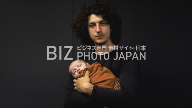 愛と温かさが伝わる親子の絆。黒背景で際立つ白人男性と赤ちゃんの写真